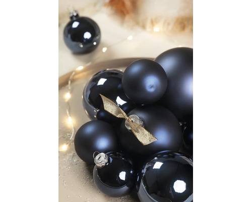 Schwarze Weihnachtskugeln in verschiedenen Größen, matt und glänzend, eine Kugel mit goldener Schleife verziert.