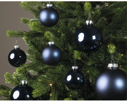 Blaue Weihnachtskugeln in verschiedenen Größen, teils matt und teils glänzend, an einem grünen Christbaum.