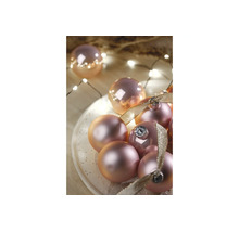 Weihnachtskugeln mit glänzender und matter Oberfläche, dekoriert mit Schleifenbändern und einer Lichterkette.