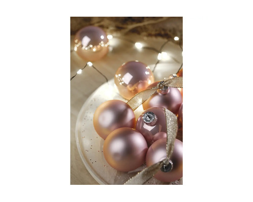 Weihnachtskugeln mit glänzender und matter Oberfläche, dekoriert mit Schleifenbändern und einer Lichterkette.