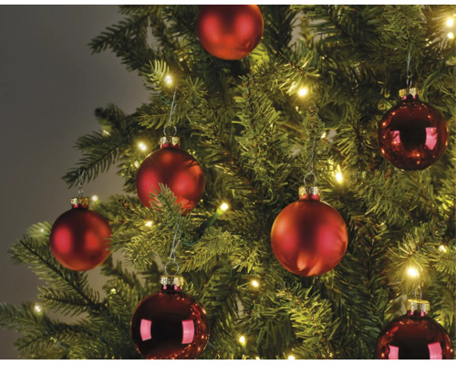 Weihnachtsbaum dekoriert mit matten und glänzenden roten Weihnachtskugeln und warmweißen LED-Lichterketten.