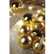 Festliche Anordnung goldener Weihnachtskugeln in glänzender und matter Optik auf einem weißen Teller mit LED-Lichterkette und Dekoband.