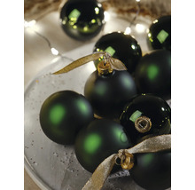 Dunkelgrüne Weihnachtskugeln in matter und glänzender Optik mit goldenen Bändern und festlicher Beleuchtung.