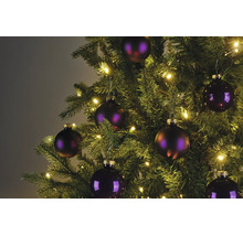 Detailaufnahme eines Weihnachtsbaums mit lila Christbaumkugeln und warmweißer LED-Beleuchtung.