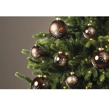 Braune Christbaumkugeln mit weißem Sternenmuster an einem geschmückten Weihnachtsbaum mit Beleuchtung.