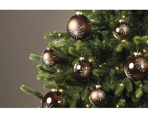 Braune Christbaumkugeln mit weißem Sternenmuster an einem geschmückten Weihnachtsbaum mit Beleuchtung.