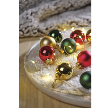 Festliches Arrangement aus Christbaumkugeln in Rot, Grün und Gold auf einem Tablett mit Kunstschnee und LED-Lichterkette.