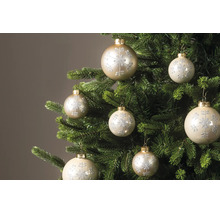 Weihnachtskugeln mit glitzerndem Schneeflocken-Muster an den Zweigen eines Christbaums.
