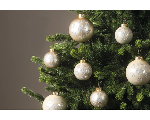 Weihnachtskugeln mit glitzerndem Schneeflocken-Muster an den Zweigen eines Christbaums.
