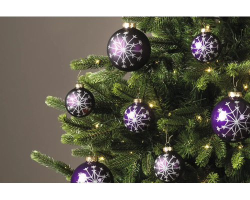 Violette Weihnachtskugeln mit glitzerndem Schneeflockenmuster an einem Weihnachtsbaum mit Lichterkette.
