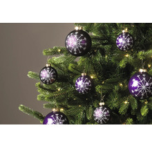Violette Weihnachtskugeln mit glitzerndem Schneeflockenmuster an einem Weihnachtsbaum mit Lichterkette.