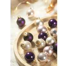 Weihnachtskugeln aus Glas in Violett und Creme auf einem runden Holzteller.