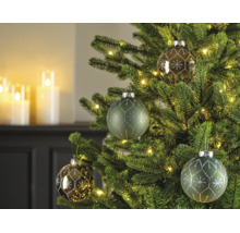 Weihnachtsbaum geschmückt mit Glas-Christbaumkugeln in Grün und Bronze, verziert mit Schneeflockenmustern, beleuchtet mit warmweißen Lichtern.