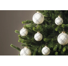Weiße Weihnachtskugeln mit silbernem Glitzermuster hängen an den Zweigen eines grünen Tannenbaums.