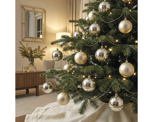 Geschmückter Weihnachtsbaum mit silbernen und champagnerfarbenen Kugeln, Lichterkette und goldenen Girlanden in einem hellen Wohnzimmer.