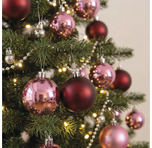 Weihnachtsbaum dekoriert mit glänzenden rosa und matten dunkelroten Weihnachtskugeln, einer Perlenkette und einer warmweißen Lichterkette.
