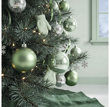 Weihnachtsbaum dekoriert mit grünen Kugeln, silbernen Discokugeln, kleinen Fäustlingen und einer Lichterkette in einem hellen Raum.