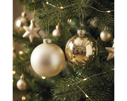 Matte und glänzende Christbaumkugeln an einem geschmückten Christbaum mit Lichterkette und Sternen.