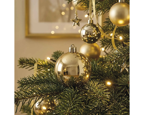 Goldfarbene Weihnachtskugeln glänzend und matt an einem grünen Weihnachtsbaum mit warmweißer Beleuchtung.