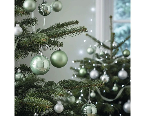 Weihnachtsbaum dekoriert mit grünen und silbernen Christbaumkugeln in verschiedenen Größen und Oberflächen sowie einer Lichterkette.