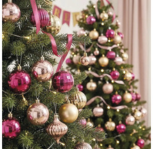 Zwei festlich geschmückte Christbäume mit rosa und goldenen Weihnachtskugeln, Bändern und warmen Lichterketten.
