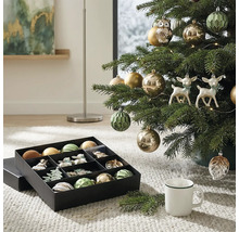 Weihnachtsbaum geschmückt mit Christbaumkugeln, Eulen- und Hirschfiguren neben einer Aufbewahrungsbox mit Weihnachtsschmuck auf einem Teppich.