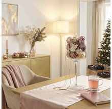Festlicher Weihnachtsraum mit Esstisch, Glaspokal voller Christbaumschmuck, geschmücktem Weihnachtsbaum und Sideboard.