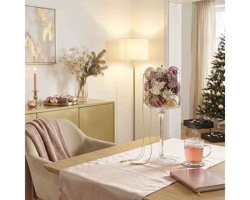 Festlicher Weihnachtsraum mit Esstisch, Glaspokal voller Christbaumschmuck, geschmücktem Weihnachtsbaum und Sideboard.