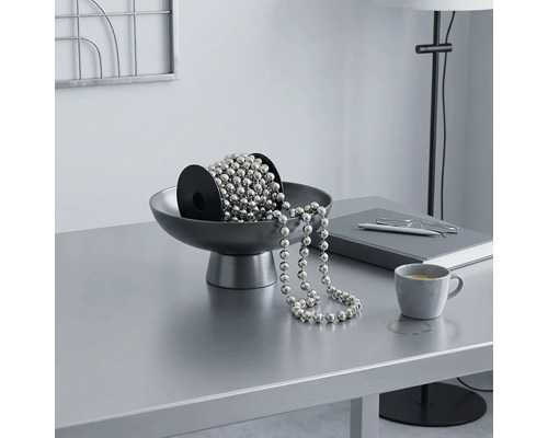 Silberne Kugelkette auf einer Spule in einer grauen Schale auf einem hellen, organisierten Schreibtisch im modernen Design.