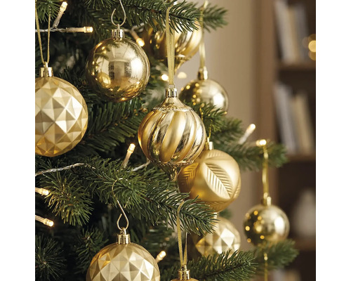 Weihnachtsbaum geschmückt mit verschiedenen goldenen Ornamenten und warmweißen Lichterketten.