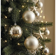 Nahaufnahme eines geschmückten Weihnachtsbaums mit matten und glänzenden Christbaumkugeln, Sternen, Lametta und einer leuchtenden Lichterkette.