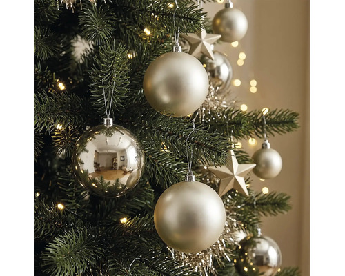 Nahaufnahme eines geschmückten Weihnachtsbaums mit matten und glänzenden Christbaumkugeln, Sternen, Lametta und einer leuchtenden Lichterkette.