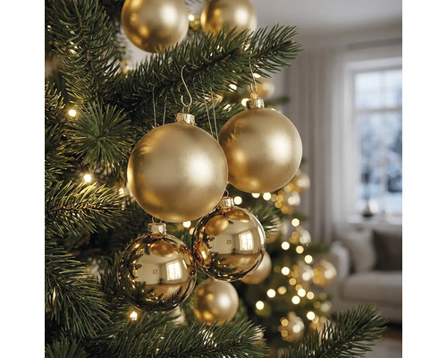 Nahaufnahme eines Christbaums mit goldenen matten und glänzenden Christbaumkugeln sowie Lichtern in einem hellen Raum.