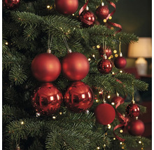 Weihnachtsbaum dekoriert mit roten Weihnachtskugeln in mattem und glänzendem Design sowie warmweißen Lichtern.
