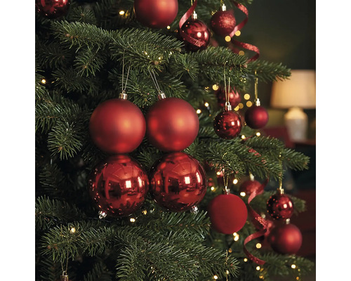 Weihnachtsbaum dekoriert mit roten Weihnachtskugeln in mattem und glänzendem Design sowie warmweißen Lichtern.