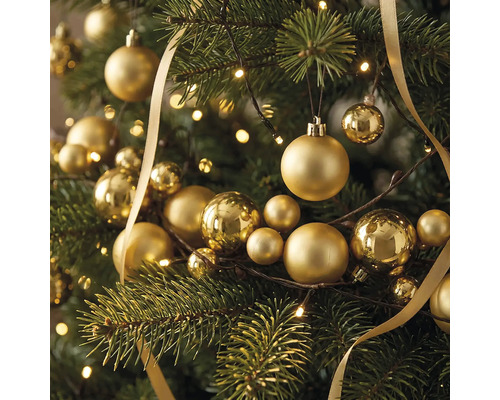 Festlicher Weihnachtsbaum geschmückt mit verschiedenen goldenen Christbaumkugeln, einem glänzenden Schleifenband und einer hellen Lichterkette.