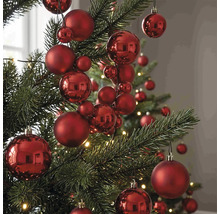 Rote Christbaumkugeln in verschiedenen Größen mit matter und glänzender Oberfläche an einem Christbaum.