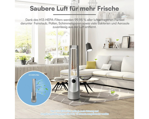 Schlanker, silberner Luftreiniger in einem hellen, modernen Wohnzimmer mit weißem Sofa. Inklusive H13 HEPA-Filter für saubere, frische Luft.