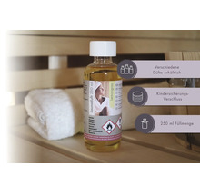 Saunaduft Lemongrass 250 Milliliter mit Kindersicherungs-Verschluss auf einer Saunabank neben einem Handtuch und einem Holzkübel.
