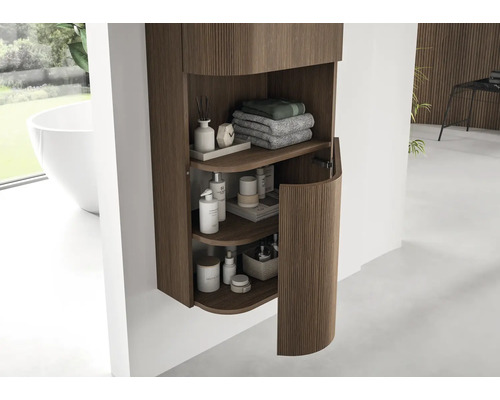 Moderner Badezimmer-Hängeschrank mit vertikalen Holzrillen und abgerundeter Tür, organisiert mit Handtüchern und Pflegeprodukten.
