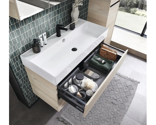 Moderner Bad-Waschtisch mit weißem Keramik-Waschbecken, Holz-Unterschrank und geöffneter Schublade mit organisierten Ablagefächern.