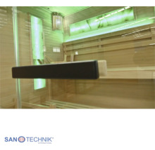 Blick durch die Glastür in eine moderne Holzsauna mit Saunabänken, integrierter Wandbeleuchtung und einem stilvollem Türgriff.