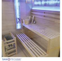 Innenansicht einer modernen Sauna aus hellem Holz mit zweistufiger Sitzbank, Saunaofen, Aufgusseimer und stimmungsvoller LED-Beleuchtung.