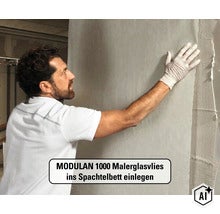 Ein Mann legt MODULAN 1000 Malerglasvlies in ein frisches Spachtelbett an einer Wand ein. (Image AI modified or generated)
