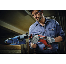 Ein Handwerker nutzt eine Einhell Akku-Säbelsäge, um ein Kunststoffrohr in einem Schraubstock zu schneiden.