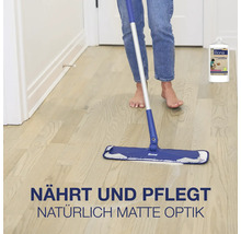 Person reinigt einen Holzboden mit einem Bona Bodenwischer und Bona Holzpflegeprodukt in einer Flasche.