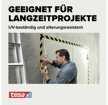 Handwerker klebt gelb schwarz gestreiftes Warnband um einen Türrahmen auf Betonwand. Tesa Logo.