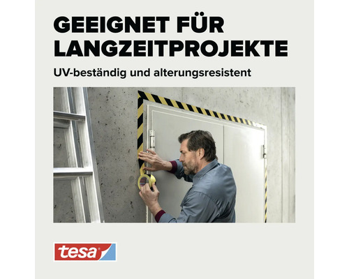 Handwerker klebt gelb schwarz gestreiftes Warnband um einen Türrahmen auf Betonwand. Tesa Logo.