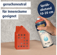 Eine Hand sprüht mit einer Belton Aqua Colors Lackspraydose in Feuerrot auf ein kleines dekoratives Haus aus Keramik.