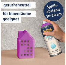 Eine Hand sprüht mit einer Spraydose Belton Aqua Colours in Verkehrs-purpur RAL 4006 ein kleines Deko Haus an für den Innenbereich.